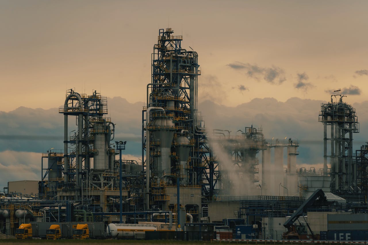 A detailed view of a refinerys towers against a cloudy dusk sky, showcasing industrial architecture.